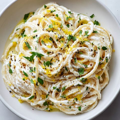 A bowl of pasta with yellow sauce and black pepper.