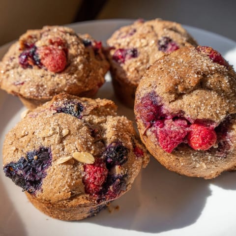 Close-up of a moist Protein Mixed Berry Muffin Top, steam rising, ready to eat.