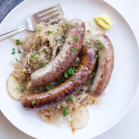 Comforting Oktoberfest Knackwurst dish garnished with fresh parsley and German mustard.  