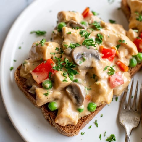 Homemade Chicken à la King featuring tender chicken and vibrant vegetables on toast.  