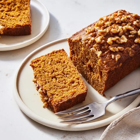 A close-up of pumpkin bread, steaming fresh from the oven, offering a delicious, moist slice.