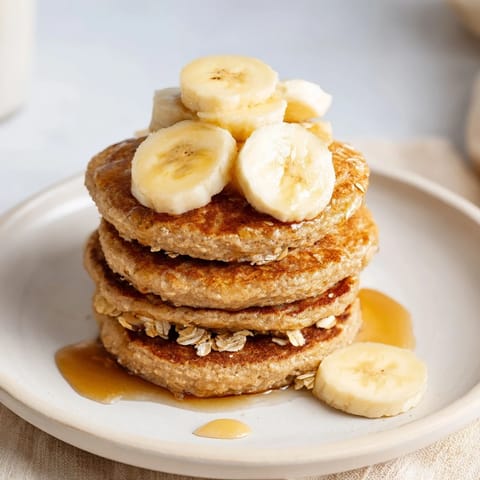 A plate of fluffy banana oat pancakes, visually appealing and perfect with fresh berries and yogurt.