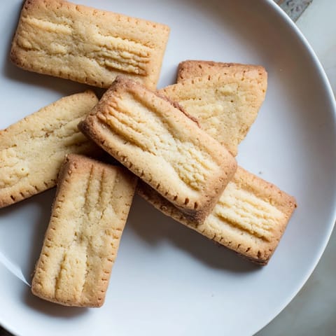 A close-up of buttery, crumbly classic shortbread cookies with a delicate dusting of powdered sugar.