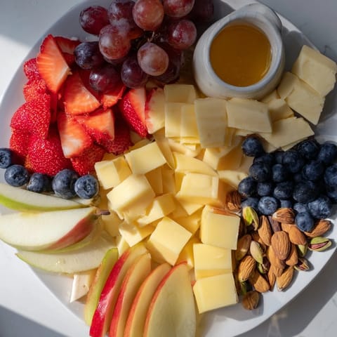 Bears Honey Pot Board features colorful fruits, cheeses, crackers, and honey, perfect for snacking.