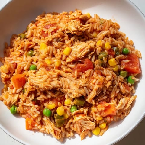 This One-Pot Chicken and Rice features a rustic look, with tomatoes and vegetables visible in the bowl.