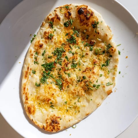 Golden, blistered garlic naan; enjoy the savory aroma of this soft, fresh-baked flatbread.