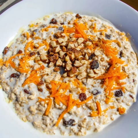 A close-up view of chilled Carrot Cake Overnight Oats with chopped nuts and raisins, ready to eat.
