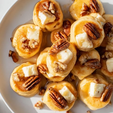 Sweet and savory Pancake Brie Bites, drizzled with honey and sprinkled with chopped pecans, ready to eat.