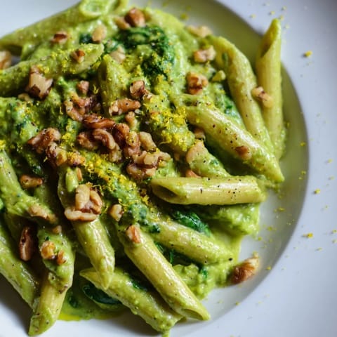 A bowl of fresh Creamy Spinach Walnut Pasta, ready to eat, with flecks of pepper on top.
