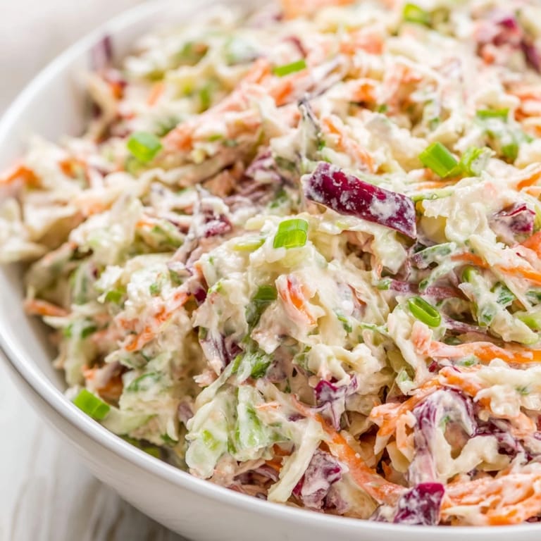 A bowl of Best Cabbage Coleslaw with vibrant orange carrots, paired with grilled pulled pork and a cold lemonade.