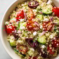 A bowl of rice with vegetables and feta cheese.
