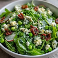 Bright lemon vinaigrette spring salad with radishes and peas, showcasing crisp greens, vibrant veggies, and a tangy citrus dressing.  