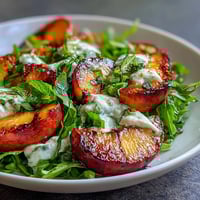Vibrant grilled peaches with creamy burrata cheese and a drizzle of honey on fresh arugula.  